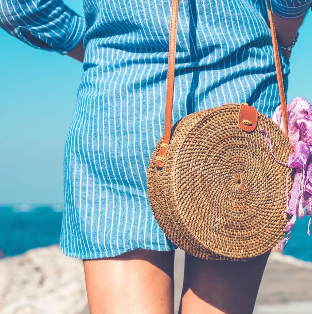 girl travels with rattan straw bag with scarf on the handle